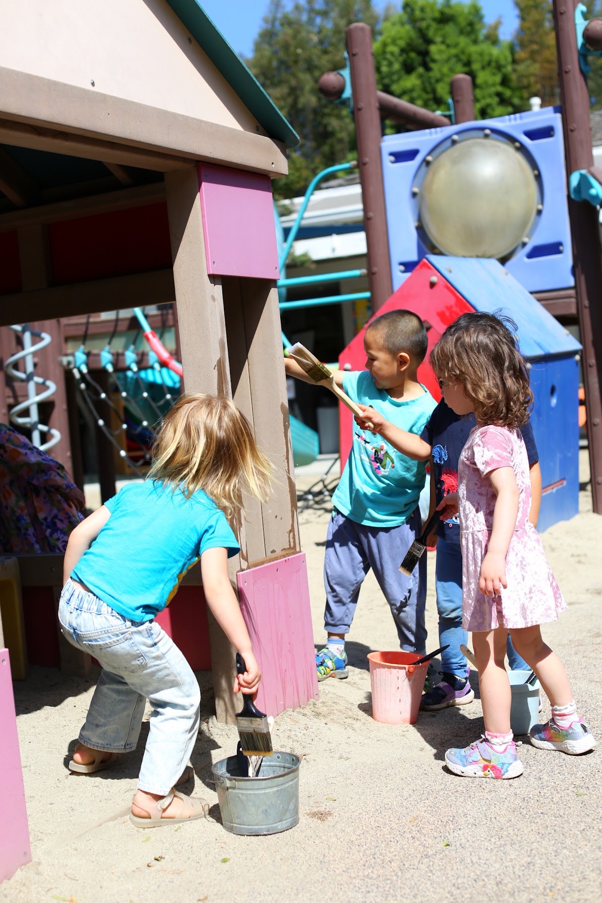 Children painting with water and brushes on the Kangaroo Room outdoor play structure